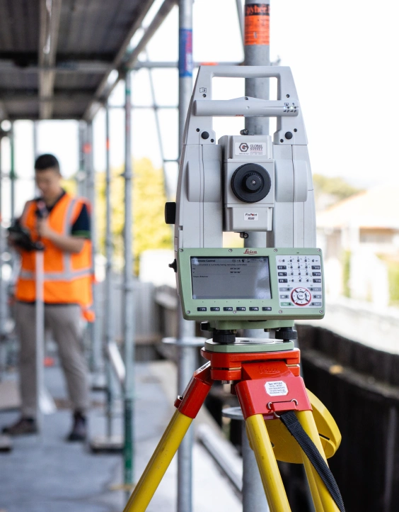 drone on a tripod with property surveyor auckland in hi-vis in background.